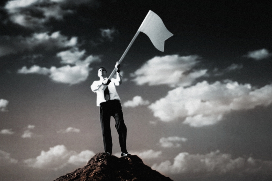 Man on Top of Hill Waving White Flag in Surrender
