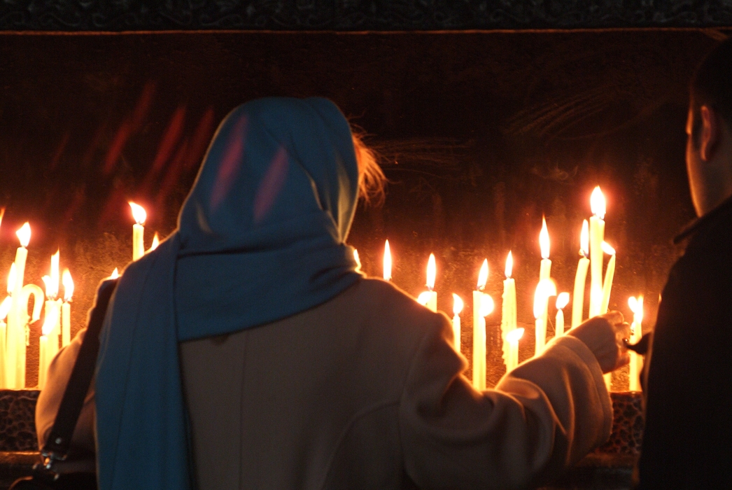 People Lighting Candle in Christian Church