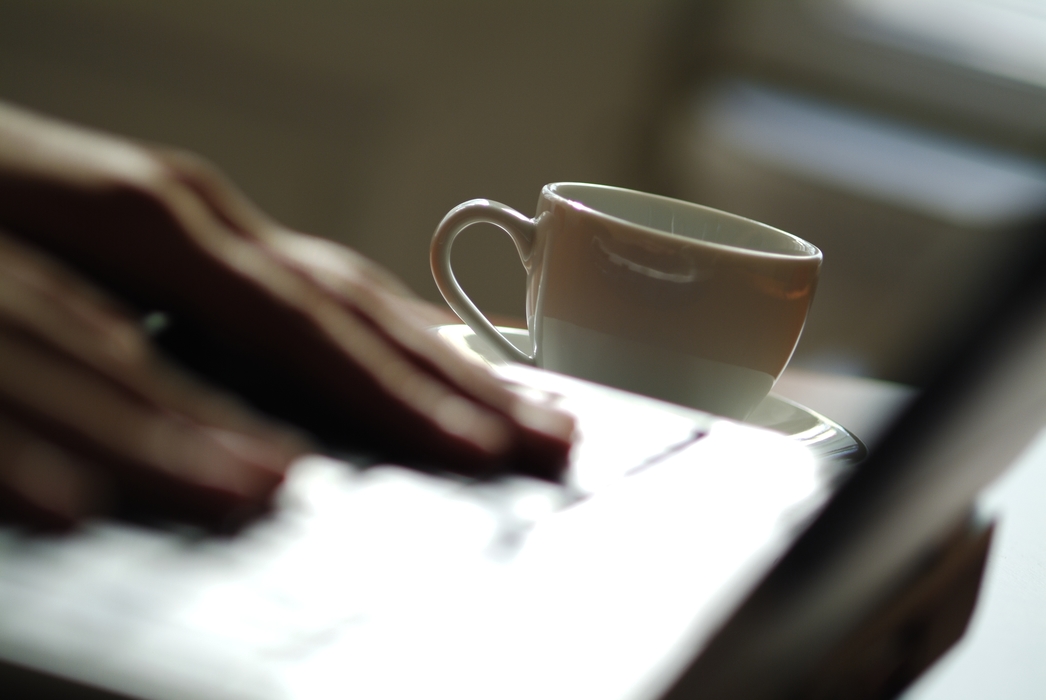 Hands Working on Laptop Computer with Coffee