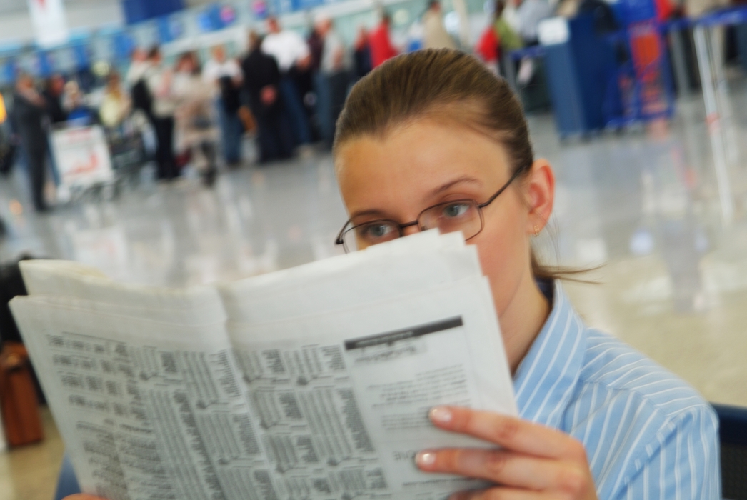 Woman Reading Newspaper in Terminal