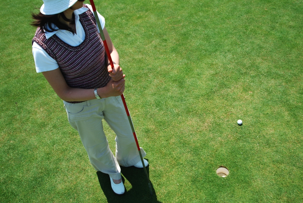 Female Golfer Holding The Flag Stick