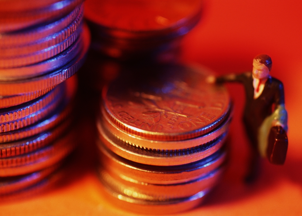 Toy Man Leaning on Stacks of Coins