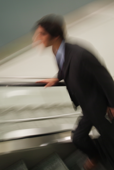 Businessman Running Up An Escalator