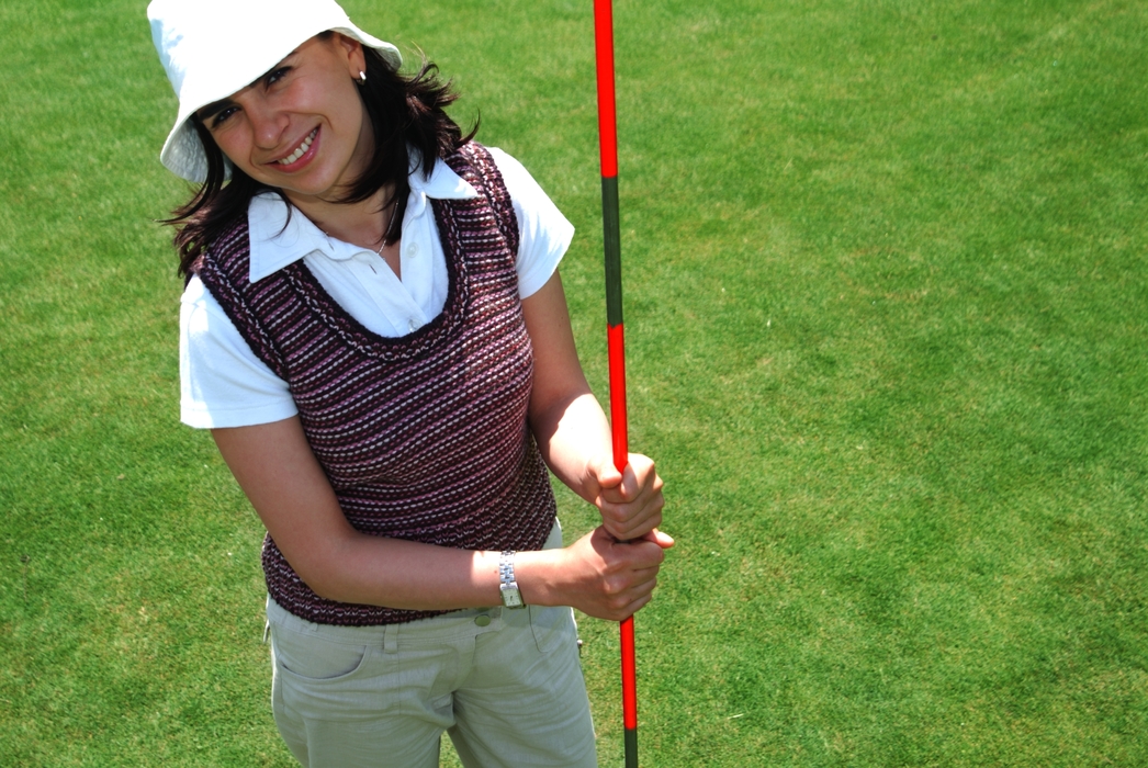 Female Golfer Holding The Flag Stick