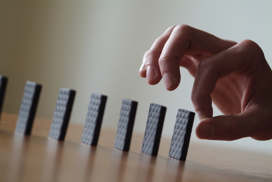 Hand Knocking Over Dominoes