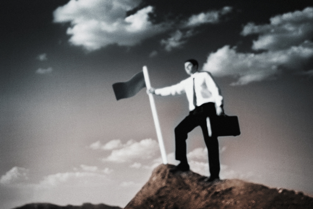 Man on Top of Hill Planting a Dark Flag