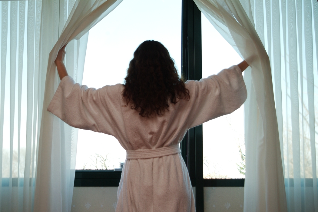 Woman Looking Out of Hotel Room