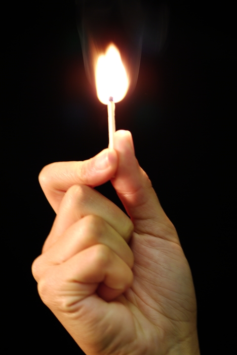 Hand Holding Lighted Match with Flame