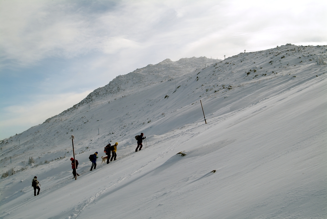 Hikers Climb Through Snow on Steep Mountain Terrain