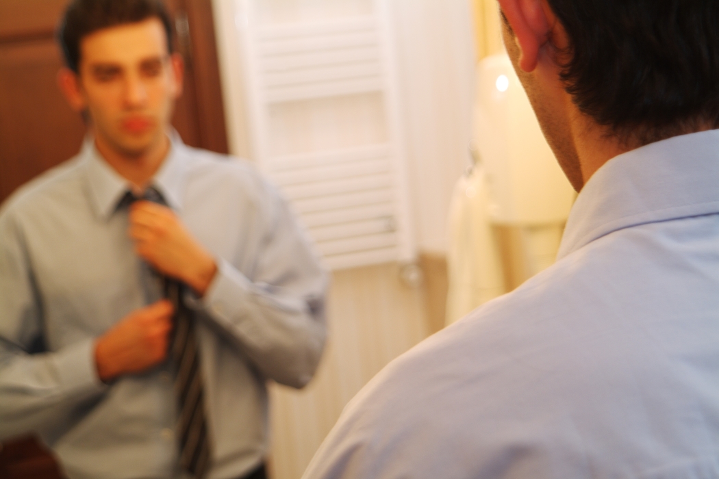 Businessman Adjusting Tie in Mirror