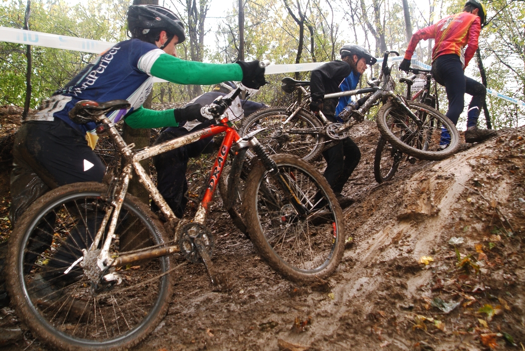 Cyclists in Mountain Bike Competition Navigate Muddy Hill