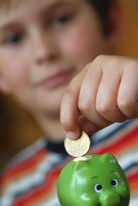 Boy Putting Coin Into Piggy Bank