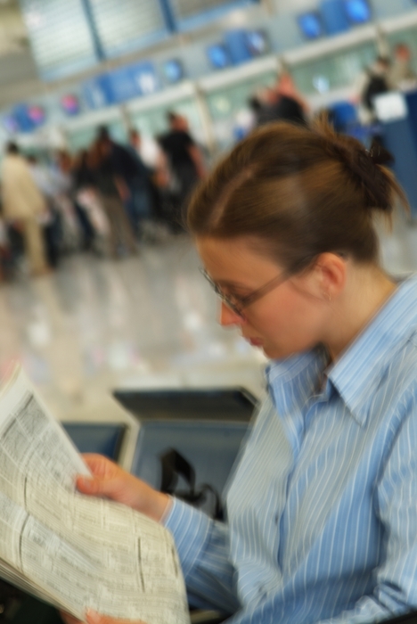Woman Reading Newspaper in Terminal