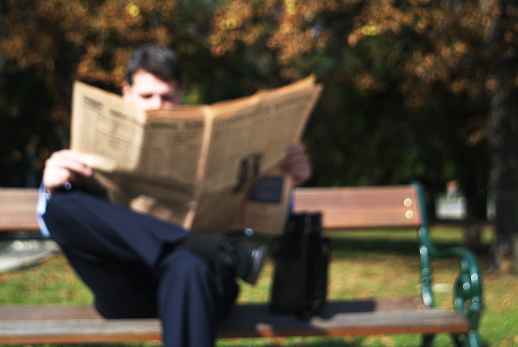 Man Reading the Newspaper on a Park Bench