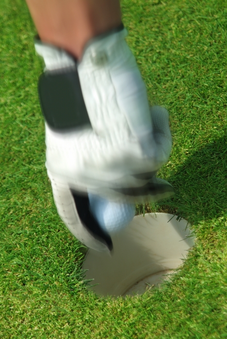 Golfer Taking Ball Out of The Cup